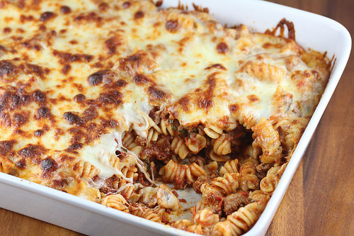 Close up of cheesy baked rotini pasta with ground beef and marinara sauce