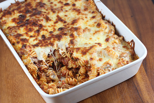 Baked rotini pasta with marinara sauce and melted cheese in white casserole dish