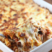 Spoonful of cheesy meaty marinara pasta bake being lifted from dish