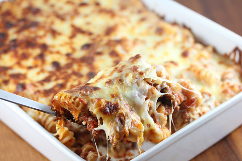 Spoonful of cheesy meaty marinara pasta bake being lifted from dish