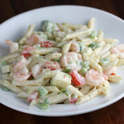Shrimp pasta salad with penne, diced vegetables, and creamy dressing on a white plate