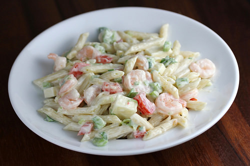 Shrimp pasta salad with penne, diced vegetables, and creamy dressing on a white plate