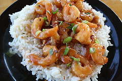 Szechuan shrimp served over white rice on a black plate