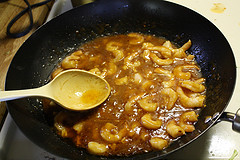 Shrimp cooking in spicy Szechuan sauce in a wok
