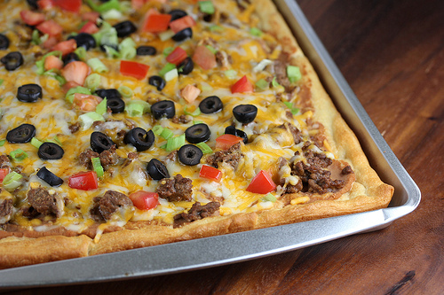 Close-up of baked taco pizza with melted cheese and fresh toppings