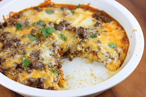 Tamale pie in a white baking dish with a slice removed
