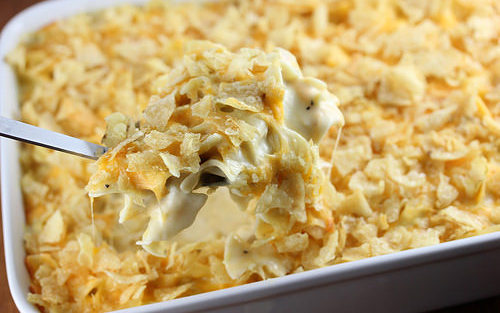 Spoonful of creamy tuna casserole topped with crushed potato chips