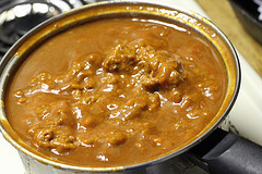 Pot of simmering red enchilada sauce with ground beef