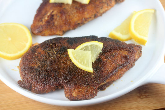 Blackened chicken topped with lemon wedges