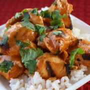 Close-up of saucy grilled chicken on white rice with fresh cilantro
