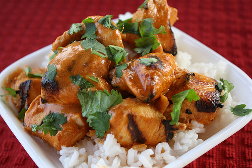 Close-up of saucy grilled chicken on white rice with fresh cilantro