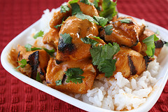 Grilled chicken pieces coated in sauce served over white rice with herbs