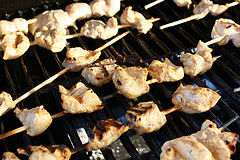Grilled chicken pieces on wooden skewers cooking over a grill