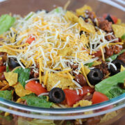 Bowl of taco salad topped with shredded cheese and Doritos