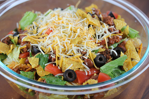 Bowl of taco salad topped with shredded cheese and Doritos