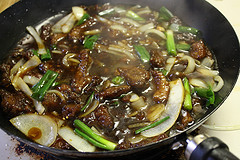 Mongolian beef simmering with onions and scallions