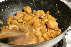 Chicken pieces cooking in a wok with sauce