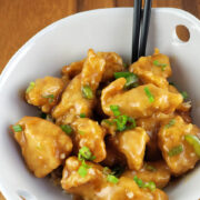 Empress chicken pieces coated in sauce with chopped green onions