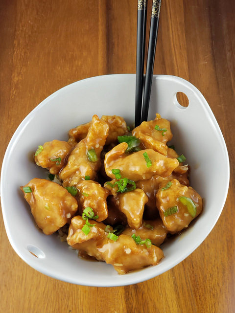 Empress chicken in a white bowl topped with green onions