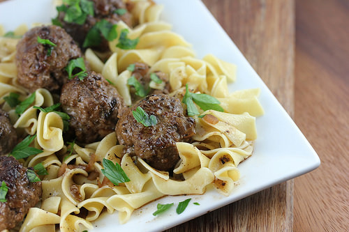 Meatballs served on a bed of egg noodles garnished with fresh parsley