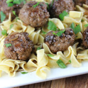 Close-up of meatballs on egg noodles with fresh parsley garnish