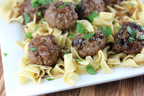 Close-up of meatballs on egg noodles with fresh parsley garnish