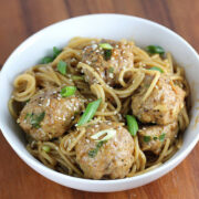 Meatballs tossed with noodles and green onions in a bowl