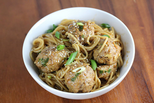 Meatballs tossed with noodles and green onions in a bowl