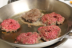 Beef patties cooking in a skillet