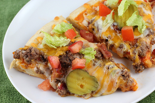 Cheeseburger pizza topped with pickles and lettuce