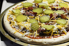 Unbaked cheeseburger pizza with pickles and bacon