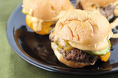 Close-up of cheeseburger sliders with melted cheese and pickles