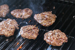 Grilled burger patties on a smoky grill