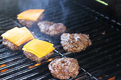 Burger patties cooking on a grill with cheese