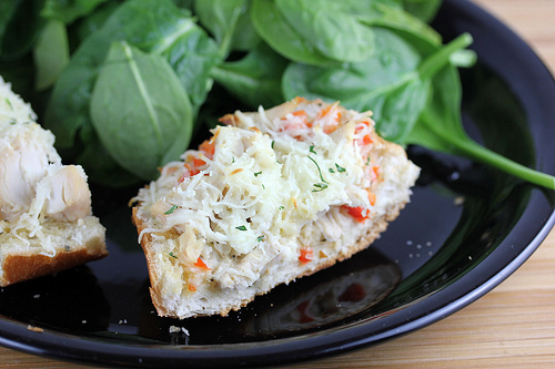 Sliced chicken french bread pizza served with fresh spinach