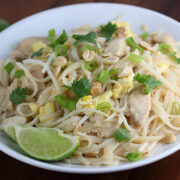 Chicken pad thai served in a bowl with peanuts, cilantro, and lime