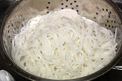 Cooked rice noodles draining in a colander