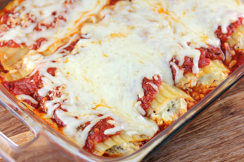Chicken parmesan manicotti in a baking dish covered with sauce and cheese