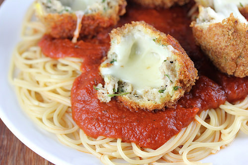 Chicken parmesan meatballs with melted cheese over spaghetti and marinara