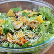 Chicken taco salad with shredded cheese, lettuce, tomatoes, and tortilla chips in a bowl