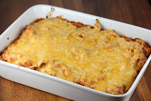 Baked chicken tamale casserole in a white dish topped with melted cheese
