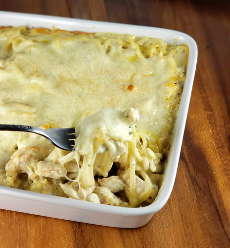 Fork lifting cheesy chicken tetrazzini from the casserole