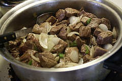 Chunks of beef cooking with onions and peppers