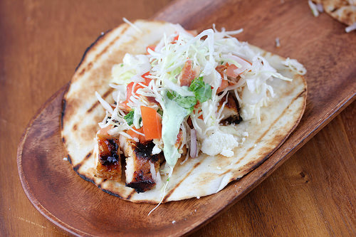 Chipotle chicken tacos topped with shredded cabbage and tomatoes on flatbread