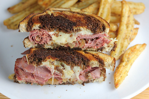 Corned beef grilled cheese halves stacked with fries on the side