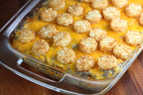 Baking dish filled with tater tot casserole topped with melted cheese