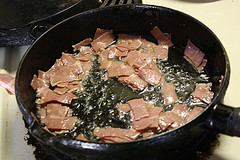 Crispy bacon pieces frying in a skillet
