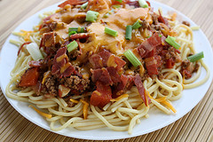 Cheesy cowboy spaghetti topped with bacon and green onions