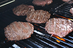 Beef burger patties cooking on grill grates