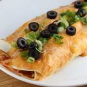 Rolled enchiladas covered in sauce with green onions